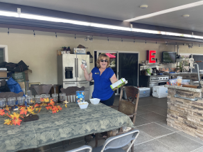 A blonde women with a royal blue shirt standing near a table as she sets up for an outdoor party