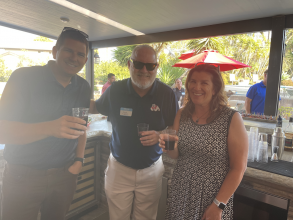 two men and a woman standing on a patio enjoying an outdoor gathering