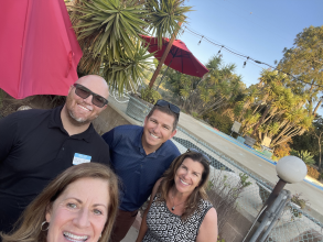 two men and two women take a selfie at an outdoor party