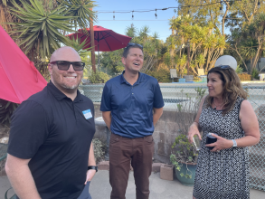 two men and a woman laughing together at an outdoor party